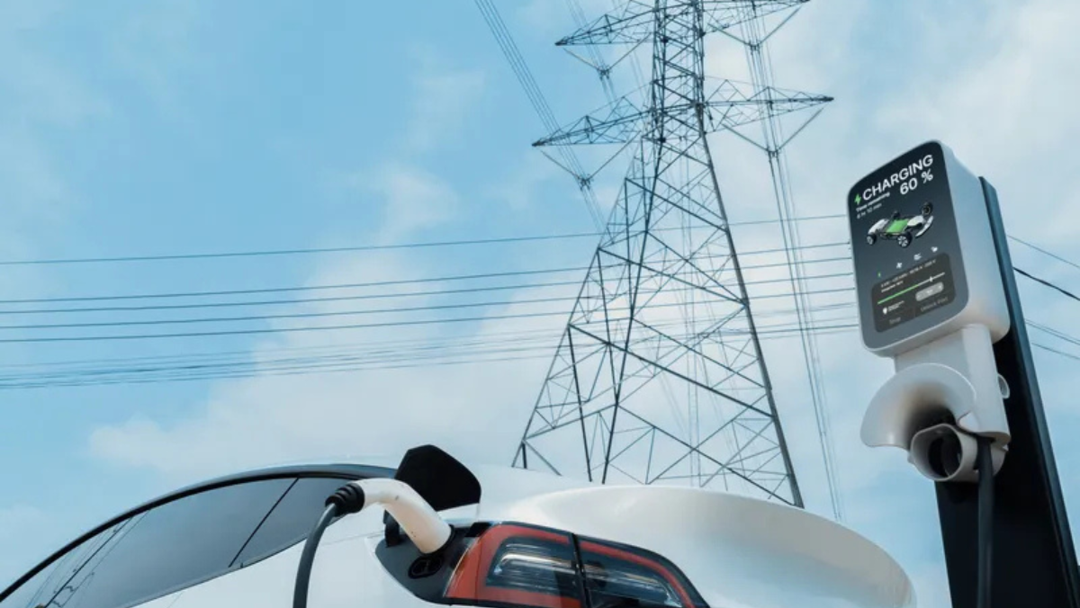 EV charging station with electric car plugged in beneath high-voltage power lines