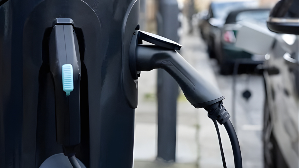Close-up of an EV charger plug connected to a street charging unit.