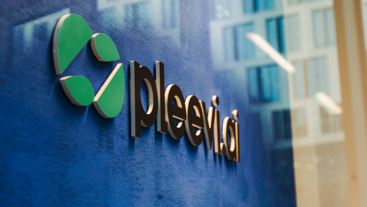 Pleevi.ai company logo displayed on a blue wall outside a modern office building.