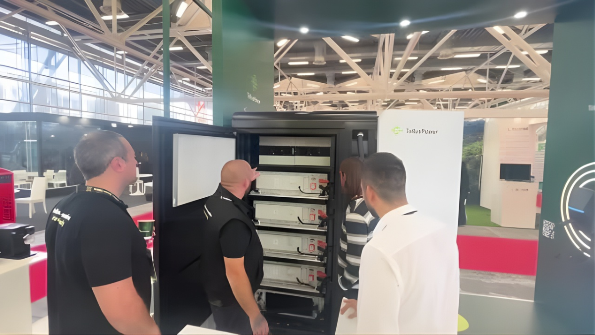 Team reviews EV charging modules inside an open equipment cabinet at an industry event.