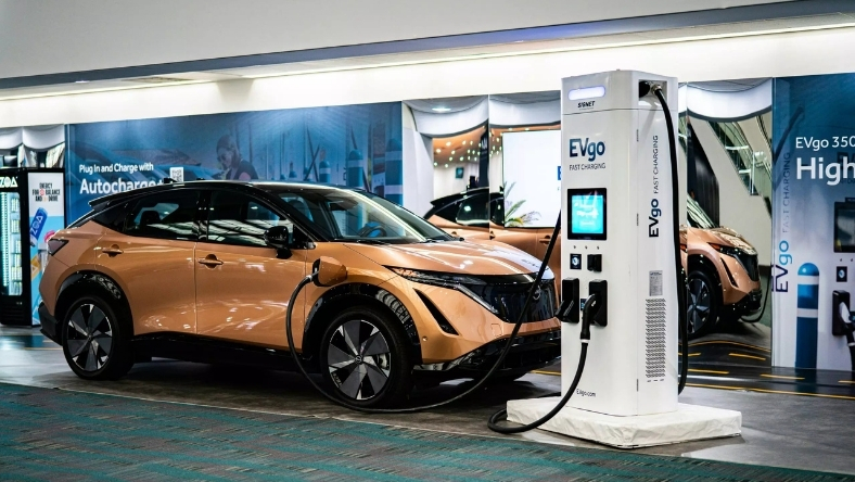 Electric vehicle plugged into a fast charging station in a public charging hub